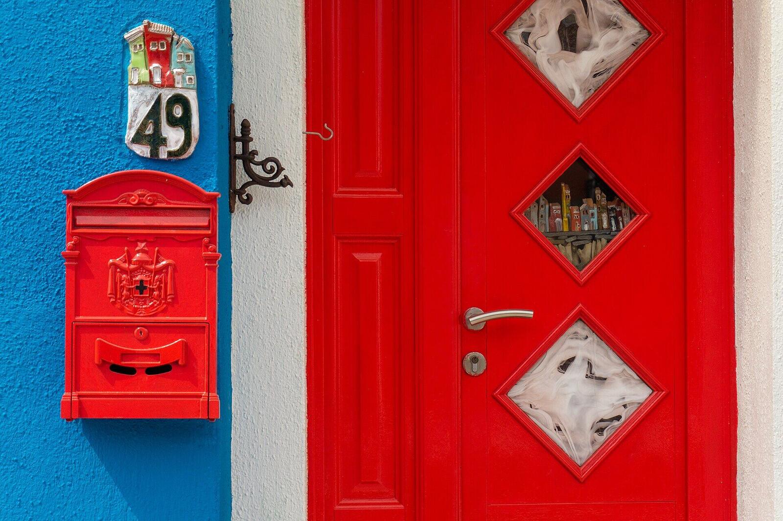 A glossy red front door set against a deep blue wall