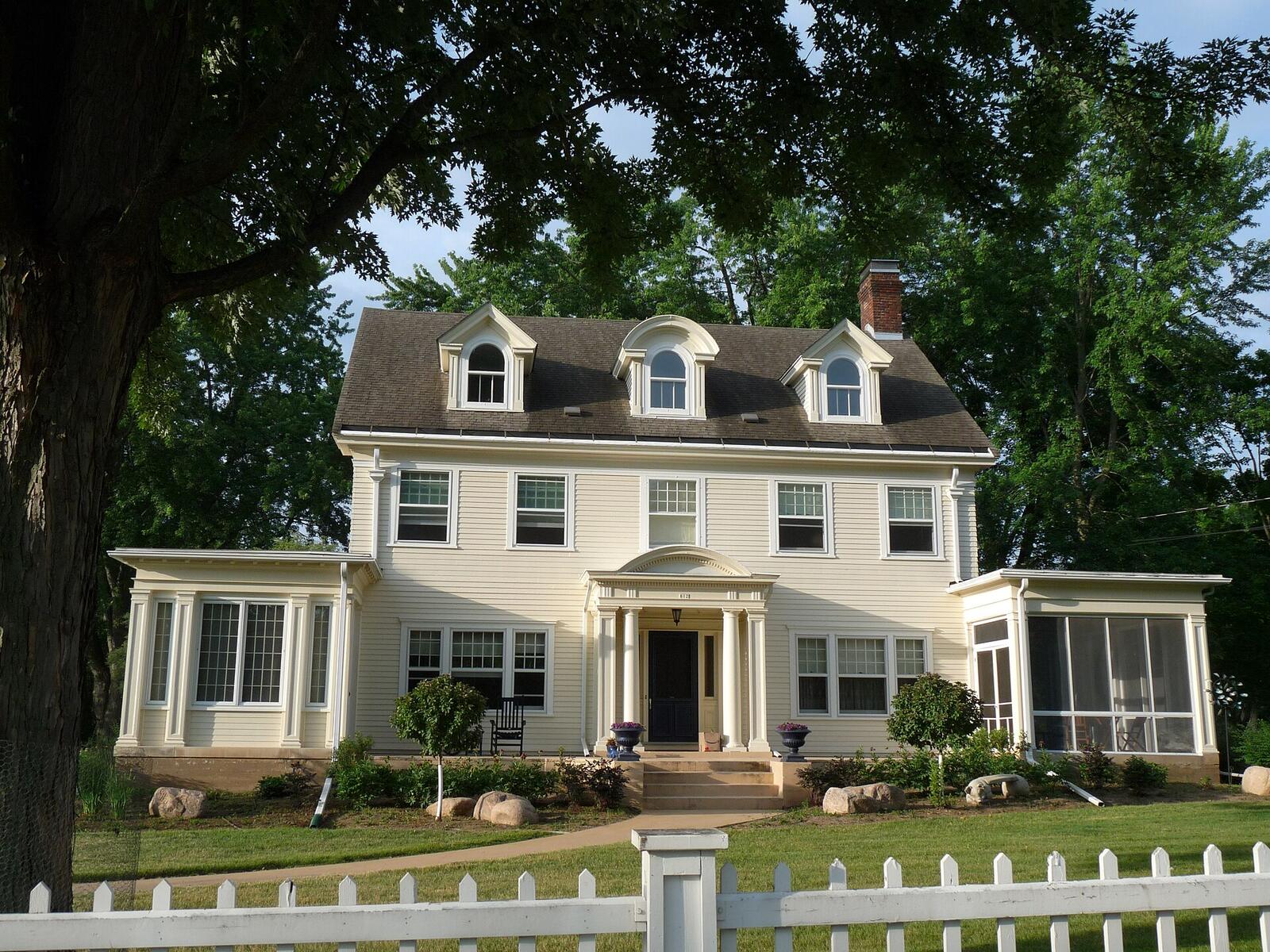 A cream Colonial Revival house with three dormers and a columned portico in Marshfield