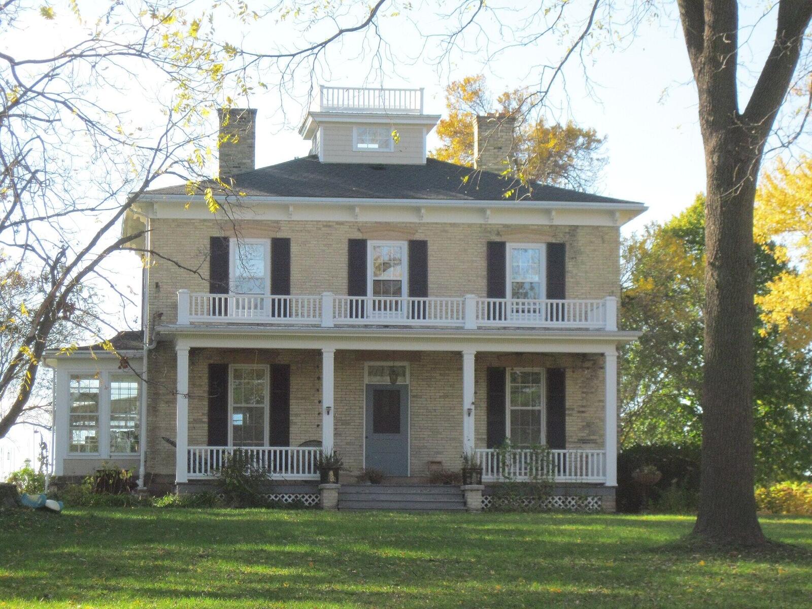 An Italianate Wisconsin farmhouse with a cupola and a two-story porch