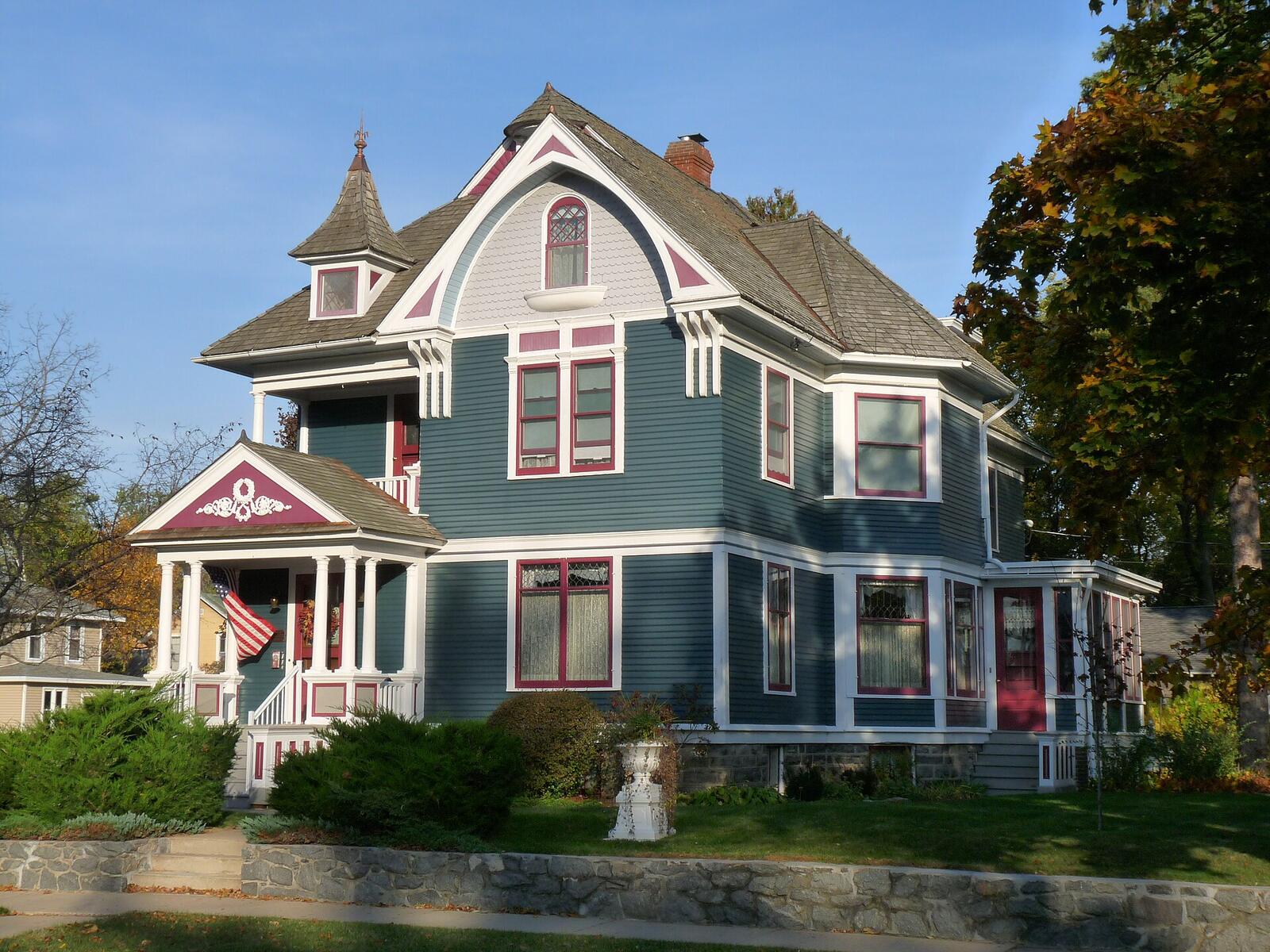 A slate-blue Queen Anne house with white trim and red accents in Stevens Point